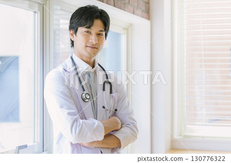 A young doctor in a white coat standing by the window A young doctor in a white coat standing by the window 130776322
