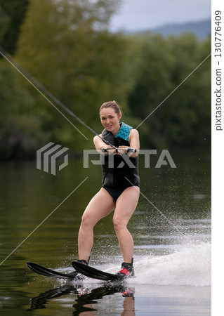 Charming young woman goes water skiing on lake 130776409