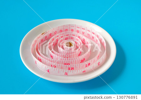 Measuring tape in white dish .Represents diet, portion control. Measuring tape in white dish .Represents diet, portion control. 130776891
