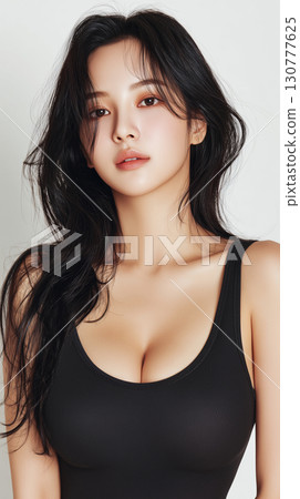 Beautiful Asian woman exuding confidence and charm in a stylish black outfit with long hair framing her face 130777625