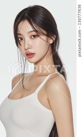 Young Korean woman in casual attire poses for a portrait with a gentle expression and flowing hair 130777636