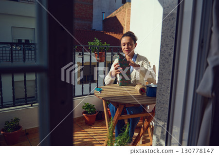 Woman Wrapping a Gift on a Balcony During a Sunny Day Woman Wrapping a Gift on a Balcony During a Sunny Day 130778147
