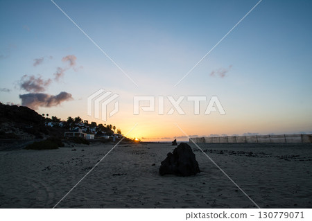 The dawn sun rises over a hill lined with buildings beyond the sandy beach on the Spanish island of Fuerteventura The dawn sun rises over a hill lined with buildings beyond the sandy beach on the Spanish island of Fuerteventura 130779071