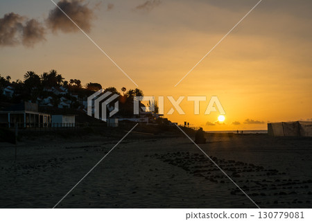 黎明時分,太陽從西班牙富埃特文圖拉島沙灘對面的一座山丘上冉冉升起,山上建築林立。 黎明時分,太陽從西班牙富埃特文圖拉島沙灘對面的一座山丘上冉冉升起,山上建築林立。 130779081