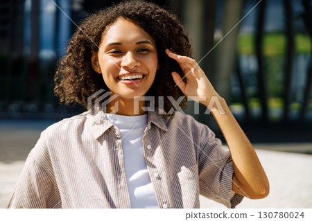A Joyful Young Woman is Brightly Smiling in a Modern Urban Setting Surrounded by Nature A Joyful Young Woman is Brightly Smiling in a Modern Urban Setting Surrounded by Nature 130780024