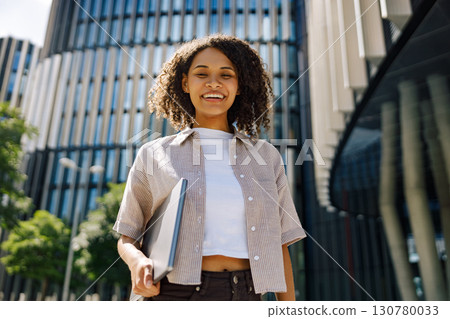 A Cheerful Woman Working Remotely on Her Laptop in a Beautiful and Lively Urban Setting A Cheerful Woman Working Remotely on Her Laptop in a Beautiful and Lively Urban Setting 130780033