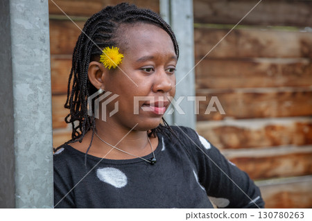 Thoughtful African American Woman with Yellow Flower in Hair Wearing Polka Dot Top Thoughtful African American Woman with Yellow Flower in Hair Wearing Polka Dot Top 130780263