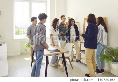 Young teacher standing in a circle with college or high school students in the classroom. 130780362