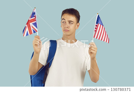 Boy student holding the flags of Great Britain and United States of America on a blue background. 130780371