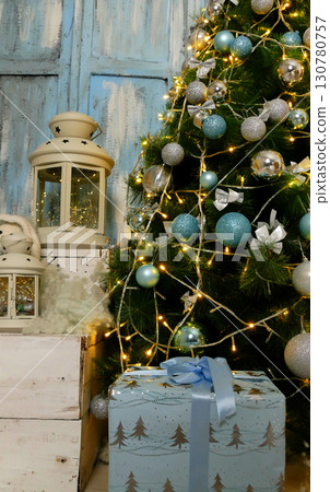 Christmas Gifts And Decorations Near Illuminated Pine Tree With Blue And Silver Glass Balls And Garland Lights   130780757