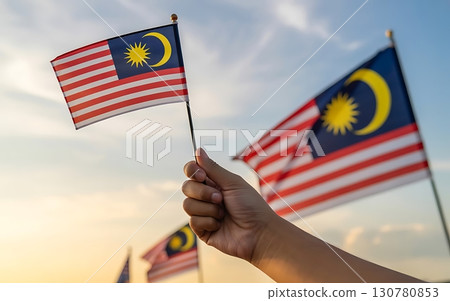 Hand holding a malaysian flag against a bright sky with more flags in the background Hand holding a malaysian flag against a bright sky with more flags in the background 130780853
