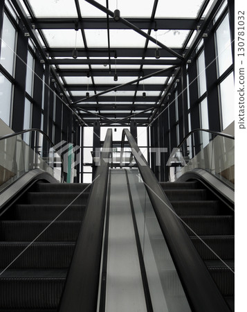 A pair of escalators with glass railing from underground floor to exit stock photo for vertical story 130781032