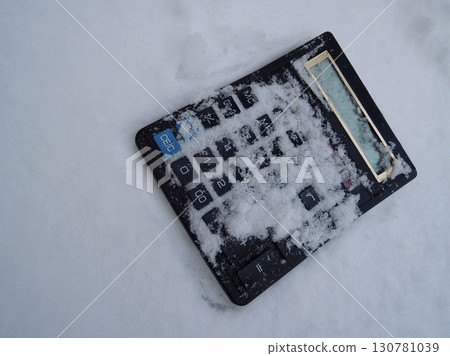 Electronic calculator thrown into the snow top view stock photo. Metaphorical image symbolizing business freeze Electronic calculator thrown into the snow top view stock photo. Metaphorical image symbolizing business freeze 130781039