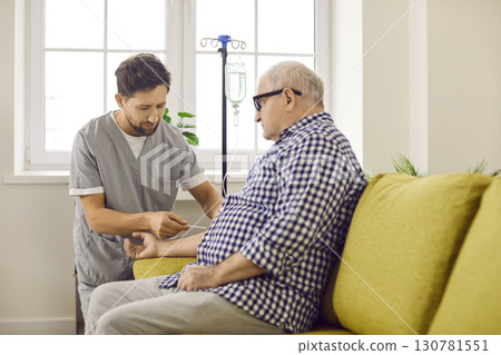 Male caregiver preparing elderly patient for IV therapy at home Male caregiver preparing elderly patient for IV therapy at home 130781551