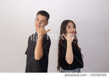 Young man and woman standing in front of a white wall 130782426