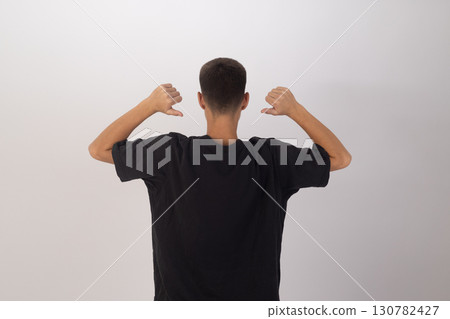 Man is seen from the back, wearing a black t-shirt, raising their arms with  130782427