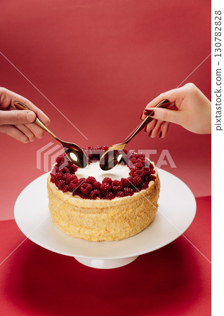Romantic dessert moment with two spoons and berry cake on red background 130782828