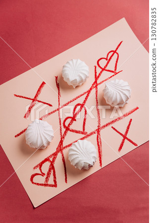 Romantic tic-tac-toe game with white marshmallows and red hearts on pink background 130782835