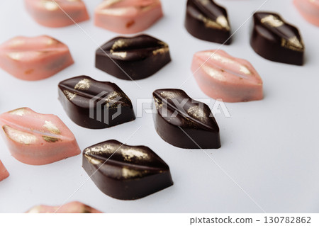 Luxury lip shaped chocolate candies with gold decor on pastel background 130782862