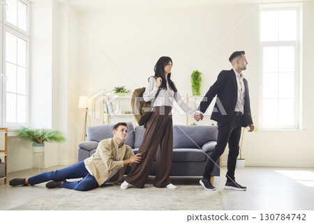 Dramatic breakup moment as woman leaves with man while another man holds her on 130784742