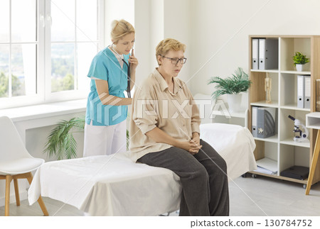 Nurse using stethoscope to examine senior patient during medical examination 130784752