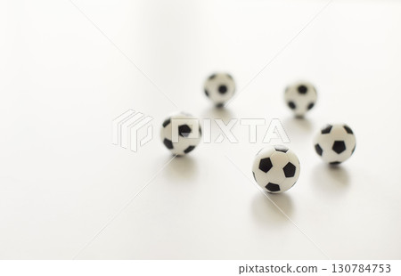 Mini soccer balls on white surface in shape of pentagon, five small toy football balls with shadow Mini soccer balls on white surface in shape of pentagon, five small toy football balls with shadow 130784753