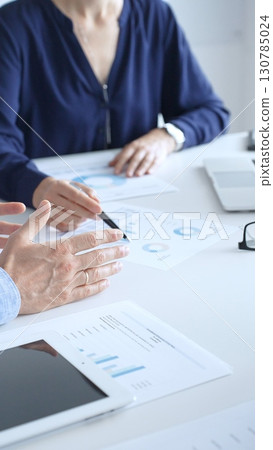Business professionals collaborating on a laptop, reviewing financial documents, and discussing project strategies in a modern office. Business people and finance concept 130785024
