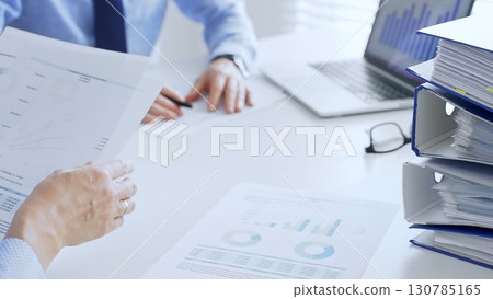 Business team working together, analyzing financial data on charts and documents, laptop and folders on white desk in office, close up of magnifying glass. Audit and taxes theme in business 130785165