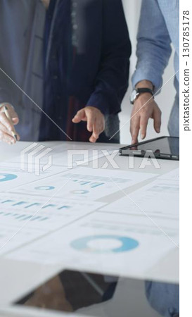 Professional team reviewing financial documents, pointing at charts on desk, collaborating to analyze data and strategize business growth. Business people concept Professional team reviewing financial documents, pointing at charts on desk, collaborating to analyze data and strategize business growth. Business people concept 130785178