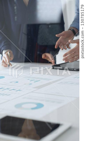 Professional team reviewing financial documents, pointing at charts on desk, collaborating to analyze data and strategize business growth. Business people concept Professional team reviewing financial documents, pointing at charts on desk, collaborating to analyze data and strategize business growth. Business people concept 130785179