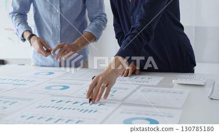 Professional business team analyzing financial reports, sharing insights and planning strategic decisions in modern workplace setting Professional business team analyzing financial reports, sharing insights and planning strategic decisions in modern workplace setting 130785180