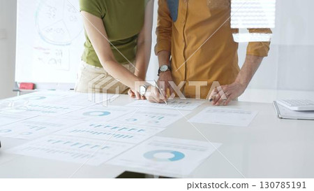 Business team members are reviewing financial data, analyzing charts and graphs, during a productive meeting in a modern office space Business team members are reviewing financial data, analyzing charts and graphs, during a productive meeting in a modern office space 130785191