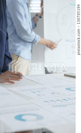 Professional team analyzing financial reports, sharing insights and planning strategic decisions in modern workplace setting. Business people concept 130785194