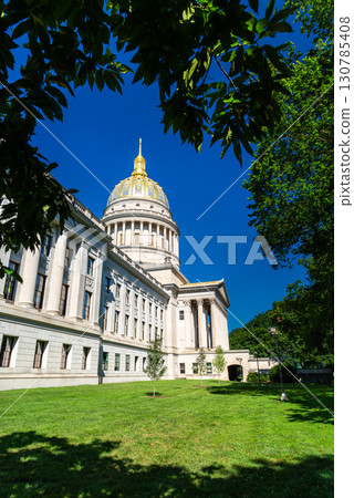 West Virginia State Capitol building in Charleston, West Virginia, United States. Designed by architect Cass Gilbert, the landmark is noted for its 23-karat gold-leaf dome, seen here framed by tree 130785408