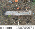 Old wooden plank lying on ground with gravel and plants 130785671
