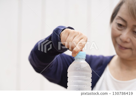 打開塑膠瓶蓋的老年婦女 打開塑膠瓶蓋的老年婦女 130786419