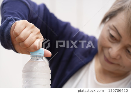 打開塑膠瓶蓋的老年婦女 打開塑膠瓶蓋的老年婦女 130786420