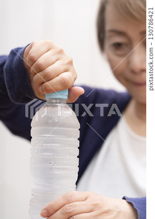 打開塑膠瓶蓋的老年婦女 130786421