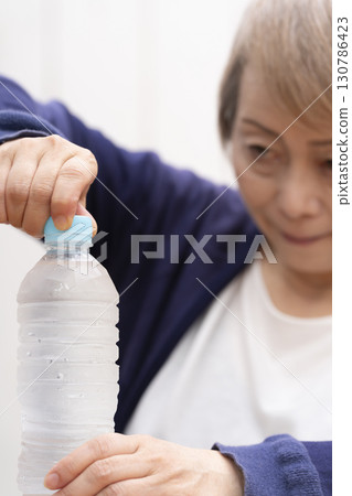 打開塑膠瓶蓋的老年婦女 130786423