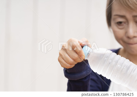 打開塑膠瓶蓋的老年婦女 打開塑膠瓶蓋的老年婦女 130786425