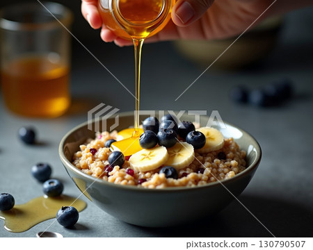 Delicious Oatmeal Bowl with Fruit and Honey Being Poured Closeup Food Delicious Oatmeal Bowl with Fruit and Honey Being Poured Closeup Food 130790507