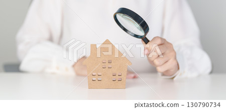 Hand hold magnifying glass over House model. mortgage, immovable assets investment, Property Inspection, Searching for real estate, purchase and rental home concept 130790734