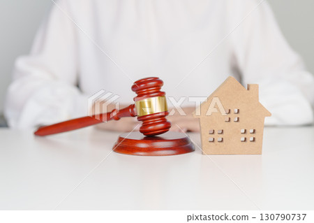 Real Estate Law, Home Insurance, property Tax, Auction and Bidding concepts. small toy house model with gavel justice hammer on desk in courthouse 130790737