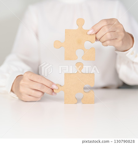 Woman connecting couple puzzle piece, wood jigsaw on table. Business solutions, mission, success, goals, strategy, Teamwork, Idea, Solution and challenge concepts Woman connecting couple puzzle piece, wood jigsaw on table. Business solutions, mission, success, goals, strategy, Teamwork, Idea, Solution and challenge concepts 130790828