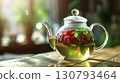 Light herbal tea with raspberries and mint in a glass teapot, with a blurred background of a cafe or home. 130793464