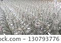 Rows of clear, empty glass bottles on an assembly line in a clean, modern factory setting 130793776