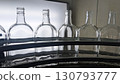A close-up shot of a set of six empty glass bottles arranged on an assembly line in a factory 130793777