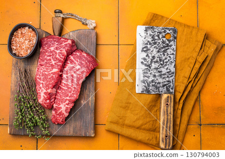 Fresh raw Denver steak, showcasing its marbled texture and rich color, perfect for grilling or pan-searing to create a flavorful meal. orange background. top view 130794003