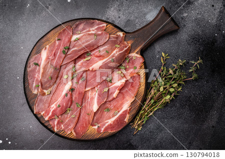 Slovenian ham, sliced cured pork meat on wooden board, Prsut. black background. top view 130794018