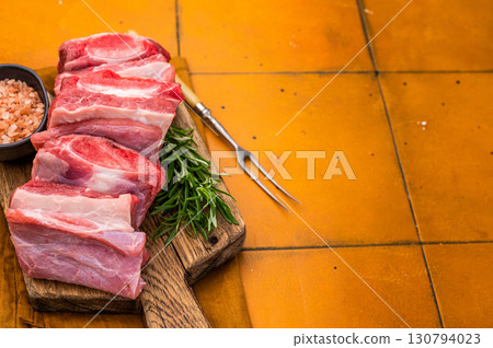 Raw beef Short chuck Ribs, fresh meat with bone on cutting board. orange background. top view Raw beef Short chuck Ribs, fresh meat with bone on cutting board. orange background. top view 130794023